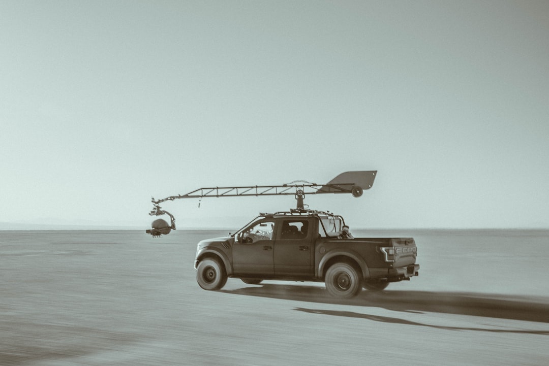 Black and white photo of a truck parked in a desert landscape