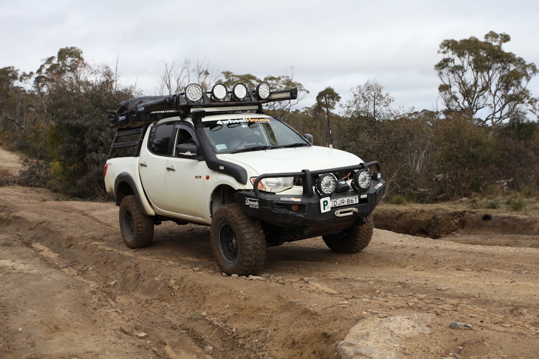 Heavily modified off-road truck on a rutted dirt track with roof rack and bull bar, ready for trail use