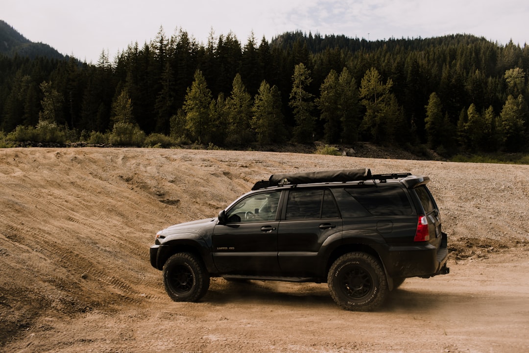 Black SUV driving on a dusty dirt trail surrounded by trees