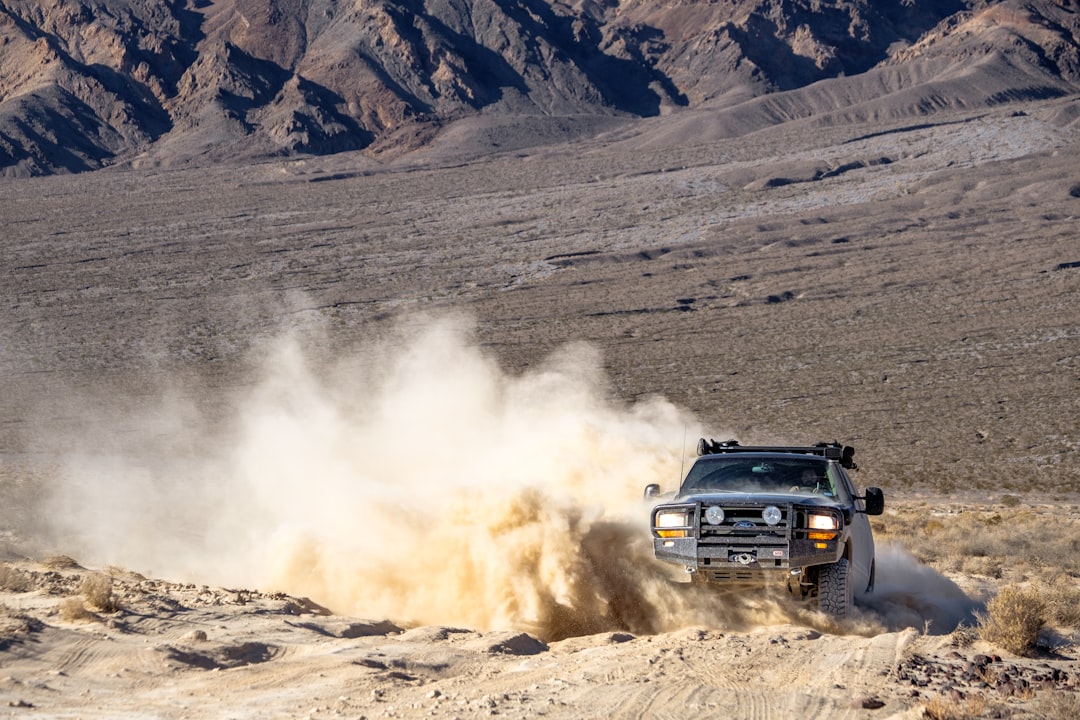 Off-road overlanding truck on a rugged dirt trail through the wilderness with mountains in the background